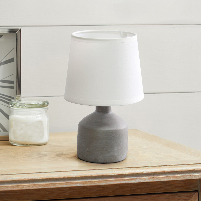 Mini ceramic table lamp with white shade and gray base on tabletop