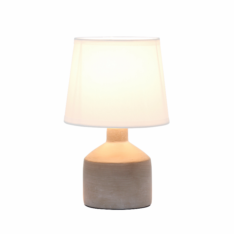 Gray ceramic table lamp with off-white drum shade glowing warmly
