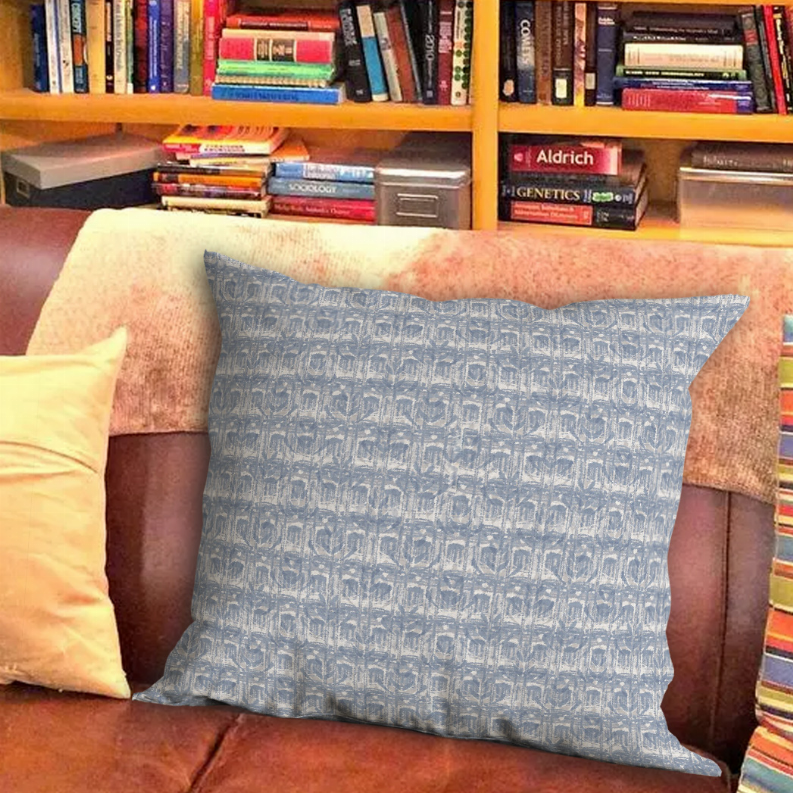 Blue patterned square throw pillow on sofa, visible seams and overlap closure