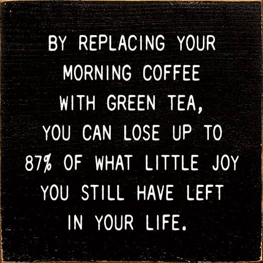 Square black decorative quote plaque with white text about green tea replacing coffee