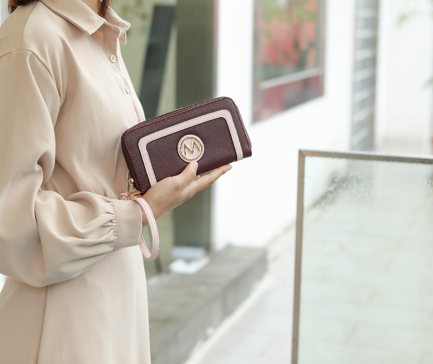 Burgundy zip wallet pouch with beige trim and round M logo, held by key-ring