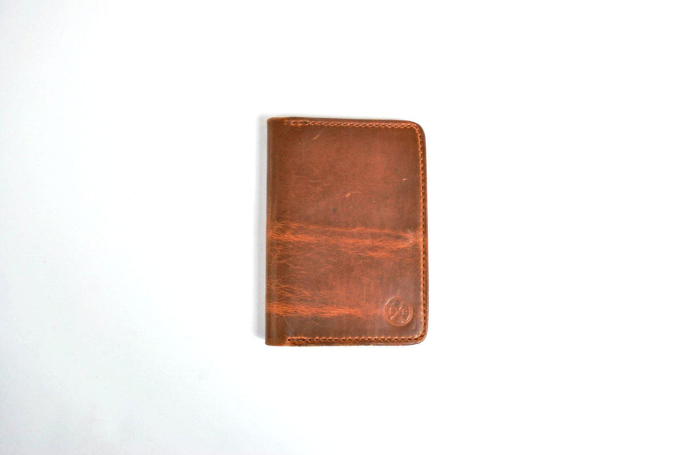 Brown carry wallet with embossed emblem on front and stitched border