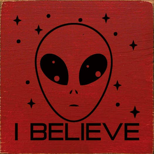 Alien-themed wall art on red background with I BELIEVE text