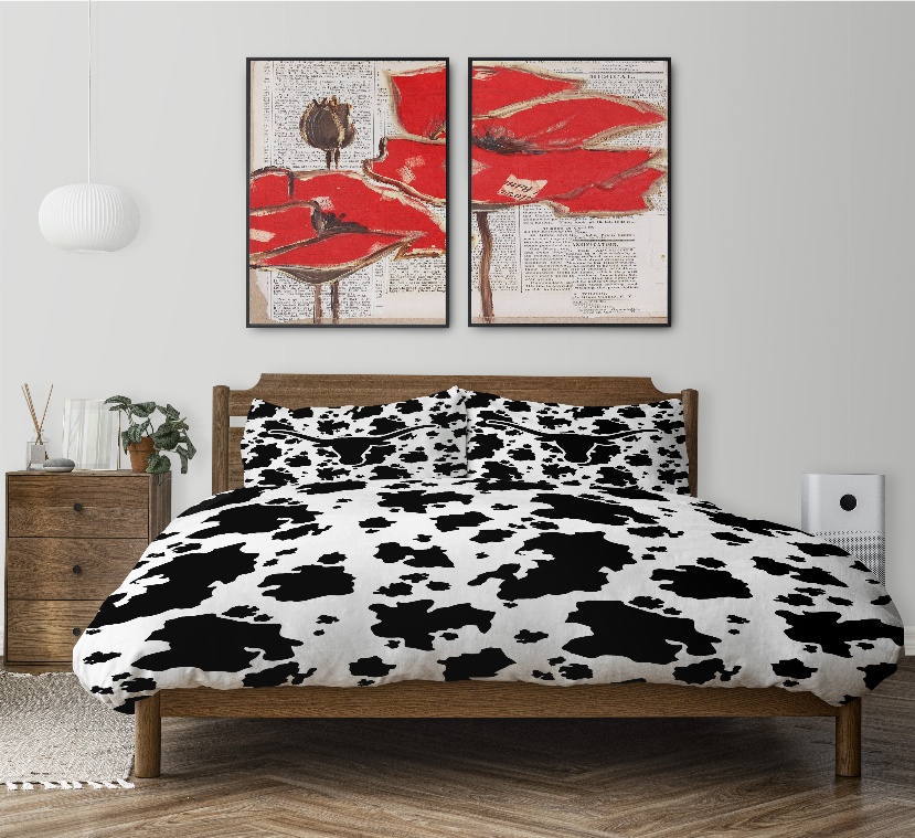 Black-and-white cow print comforter set on a wooden bed with two pillow shams