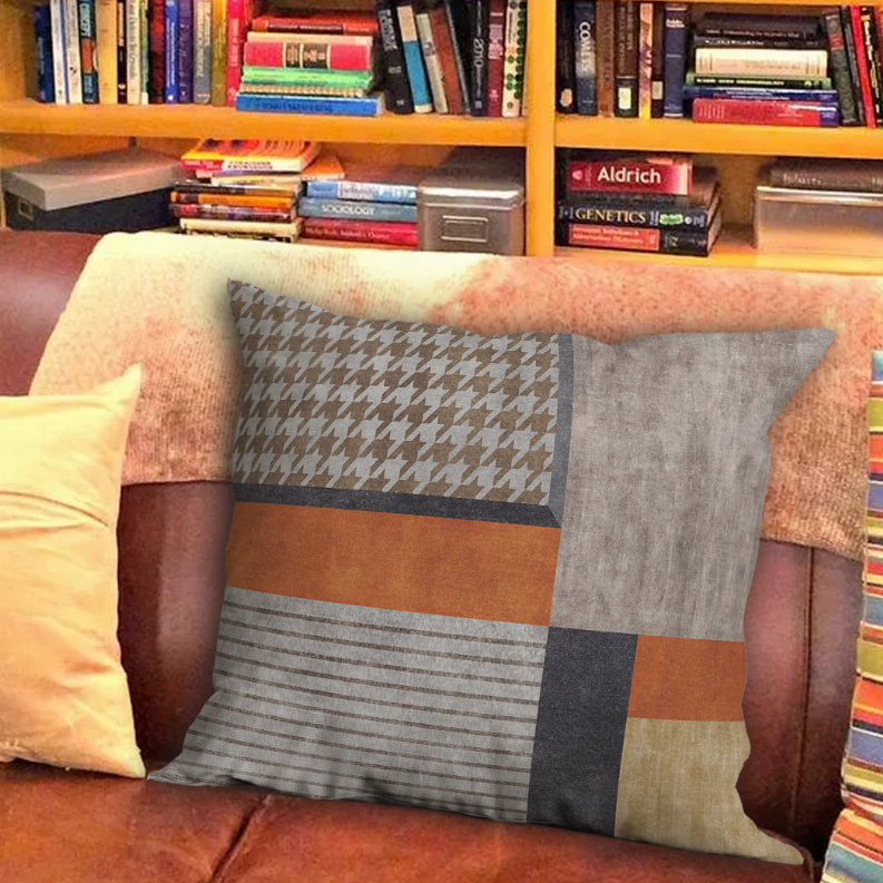 Square patchwork pillow featuring houndstooth and striped sections in gray, orange and beige