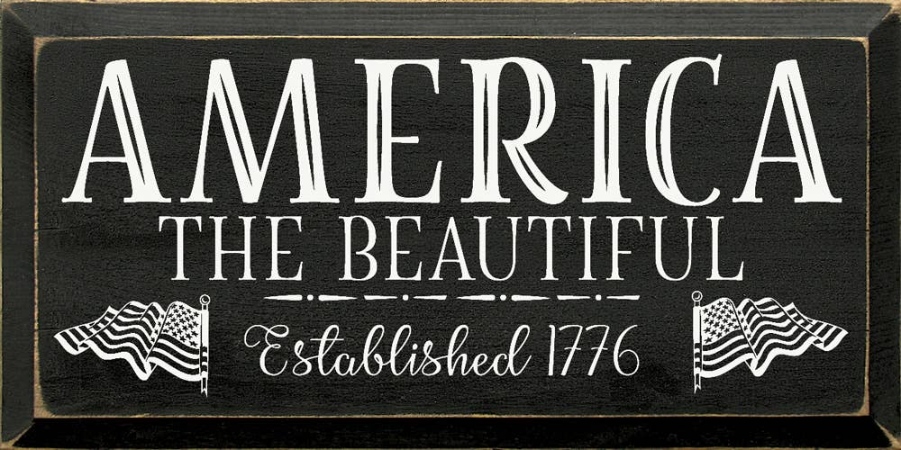 Decorative America sign with bold white text “AMERICA THE BEAUTIFUL” and “Established 1776”