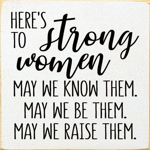Wood sign with black lettering: Here's to Strong Women, may we know them.