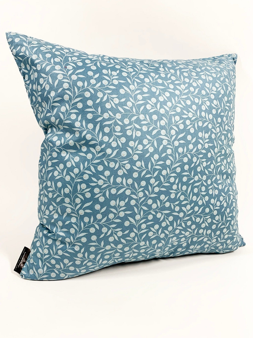 Teal throw pillow with white leaf pattern, corner detail with small black tag