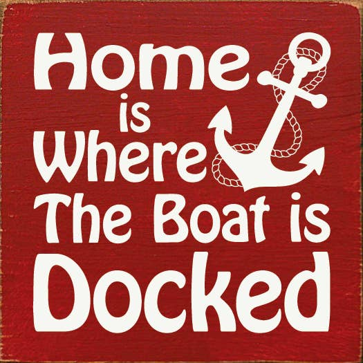 Red nautical wall sign with white anchor and text: "Home is where the boat is docked"