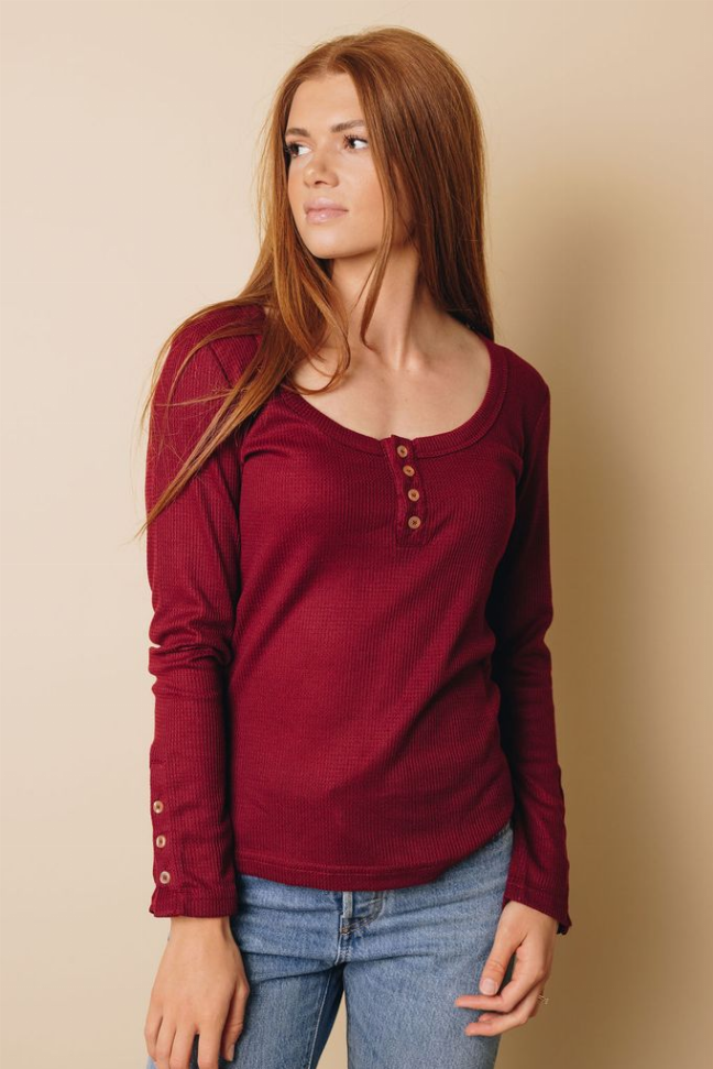 Burgundy long-sleeve henley button top, rounded neckline and cuff buttons, front view