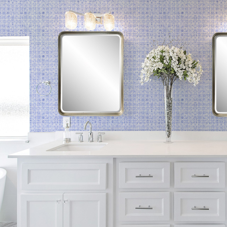 Blue repeating motif wallpaper wall behind white vanity and mirrors