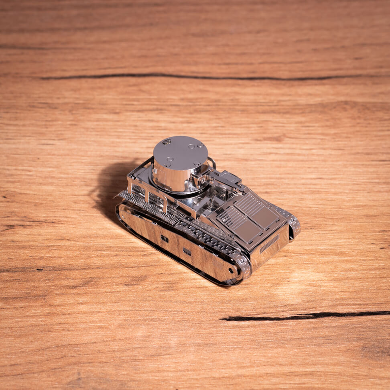 Mini metal tracked tank model on tabletop with round turret housing