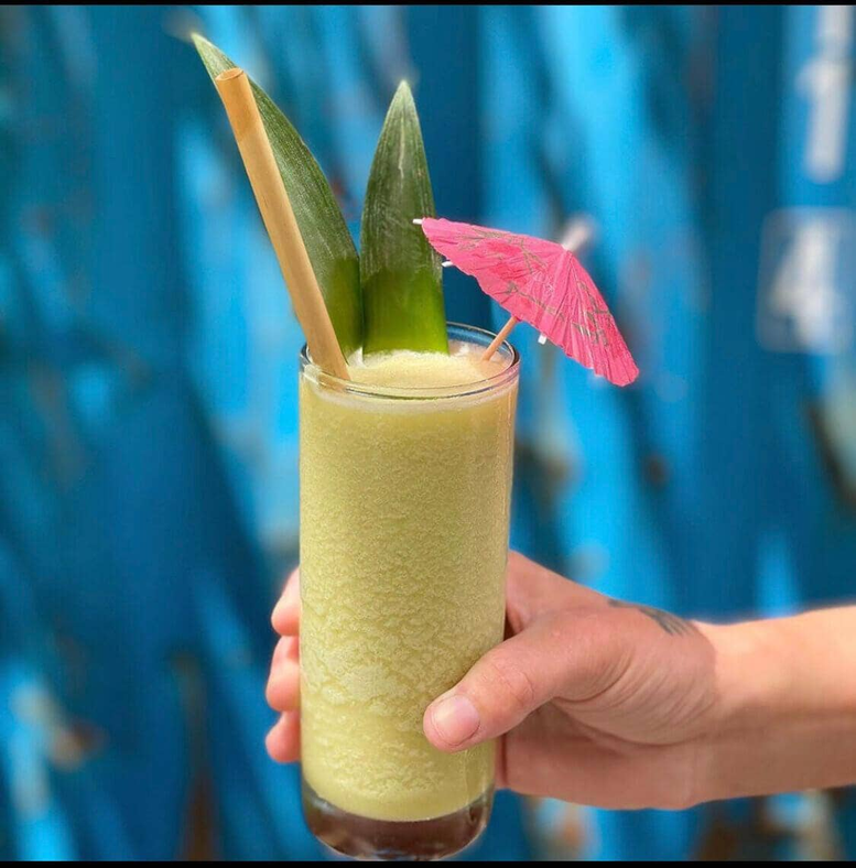 Tall reed drinking straws in a clear glass held by a hand.