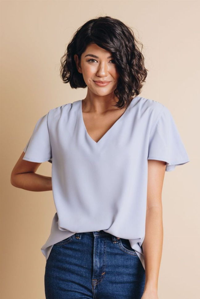 Light blue V-neck short-sleeve blouse with draped front and flutter sleeves