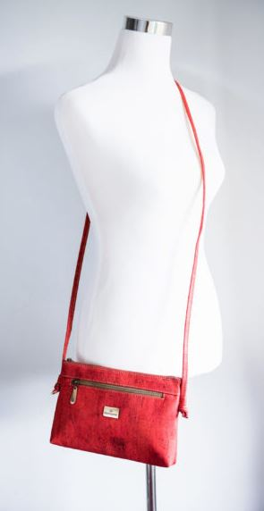 Red cork crossbody bag on adjustable strap with front logo plate and zipper pocket