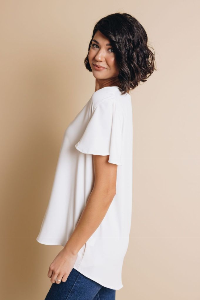 White short-sleeve top with relaxed drape and curved hem, side view