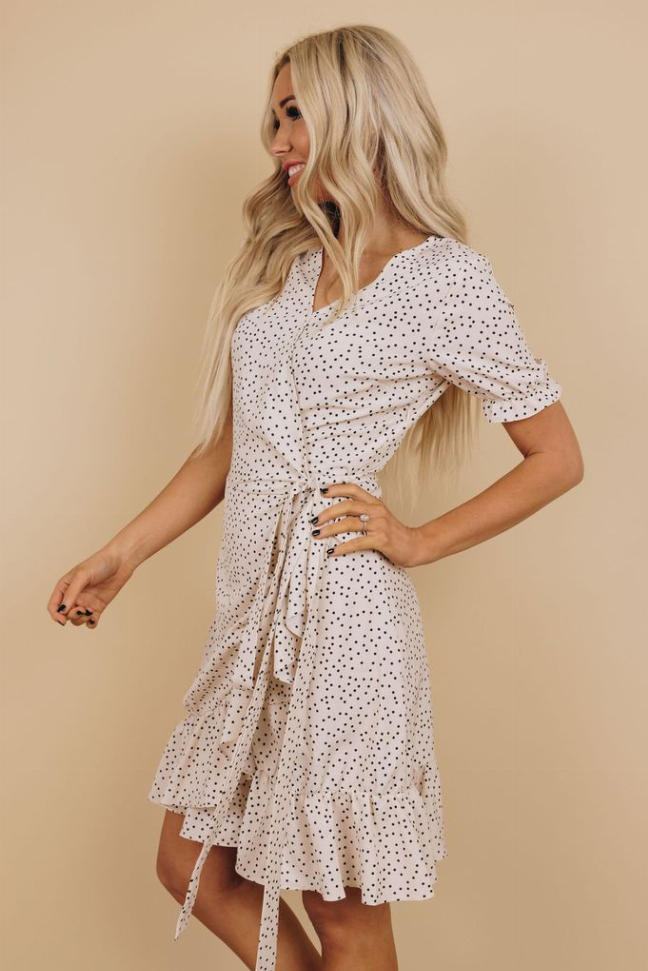 White dotted wrap dress side view with short sleeves, V-neck, tie waist, ruffled tier hem