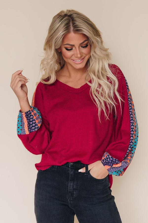 Red thermal top with blue patterned sleeves and cuffs, crew neck, long sleeves