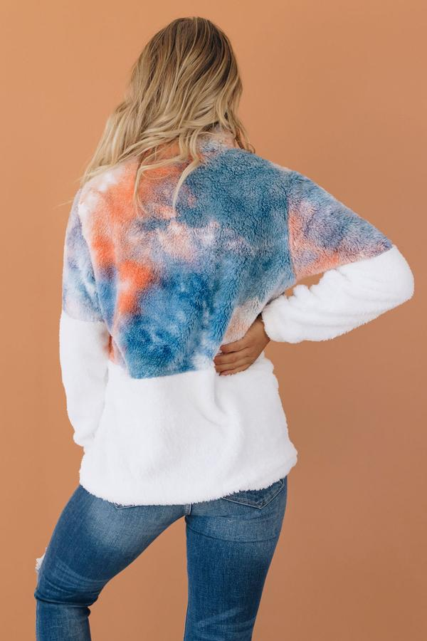 Tie-dye fuzzy pullover half-zip, back view with blue/orange patches; hands in pockets