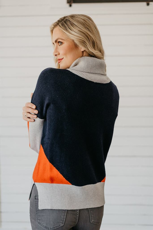 Color-block turtleneck sweater with dark navy back, orange lower panel, and gray collar