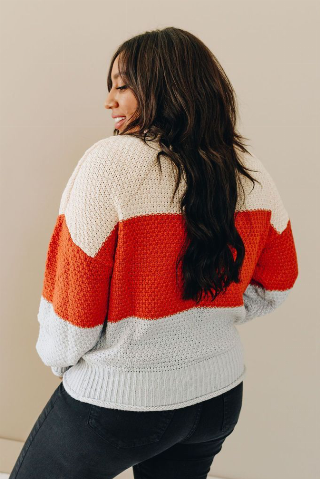 Color-block turtleneck sweater with white and red-orange horizontal stripes, back view