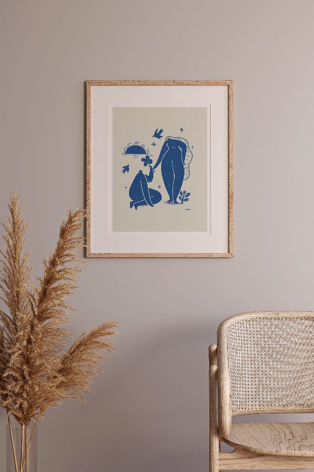 Framed wall art print with blue illustrated couple, dark wood frame; pampas grass nearby