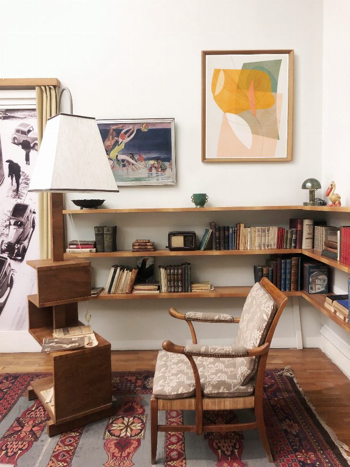 Framed abstract watercolor print near bookshelf, showing orange, green, and peach shapes