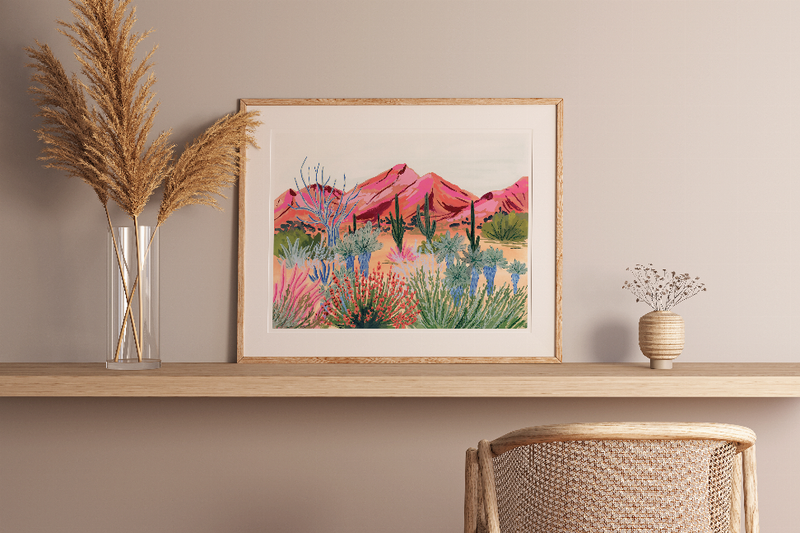 Framed desert landscape print with bright pink vegetation and a wooden picture frame
