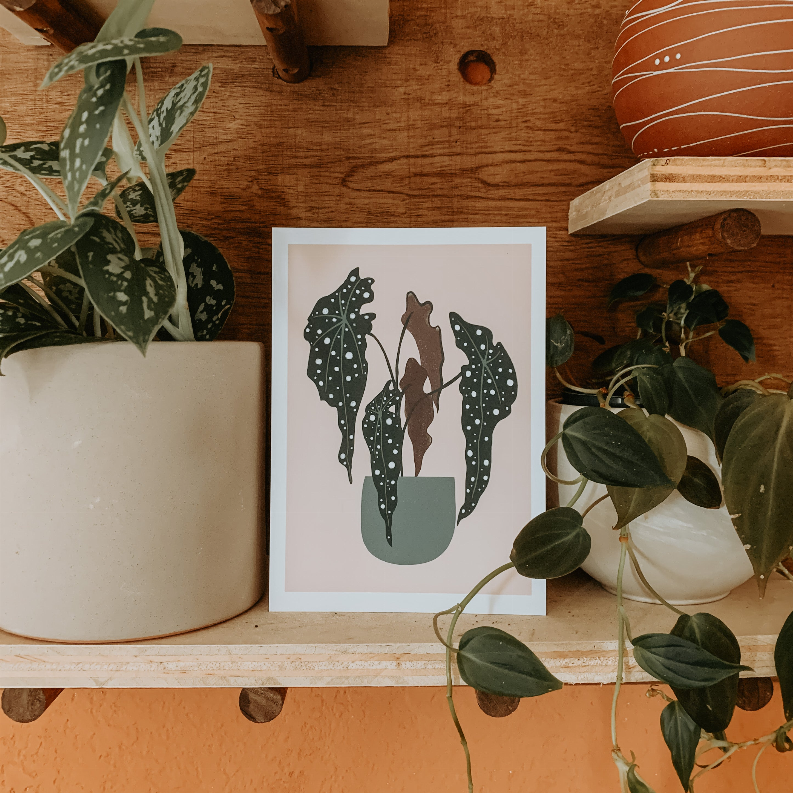 Framed botanical print with dark green polka-dot leaves and a potted plant silhouette