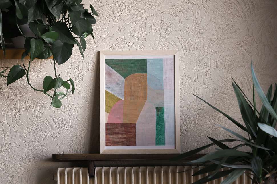 Framed abstract wall art print on wall above radiator, geometric blue, green, and orange blocks