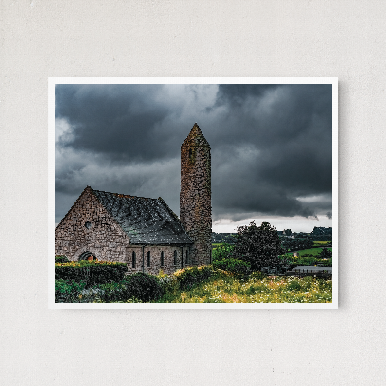 Framed landscape print of stone church with tall tower, stormy clouds