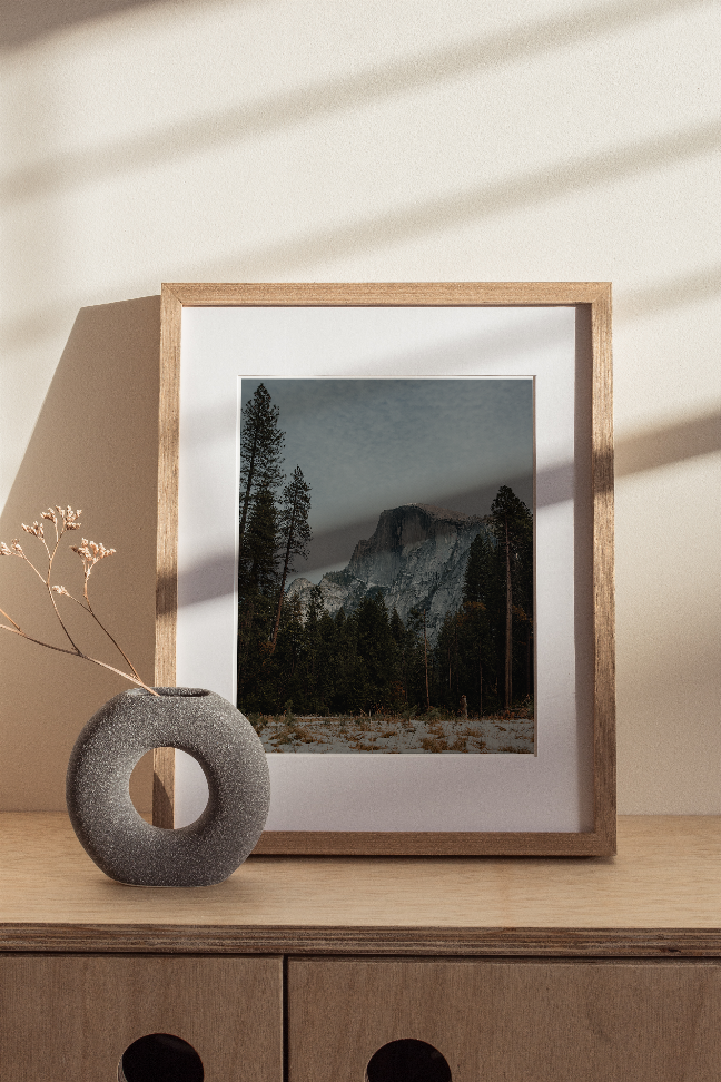 Half Dome landscape print in a light wood frame with pine trees and snow