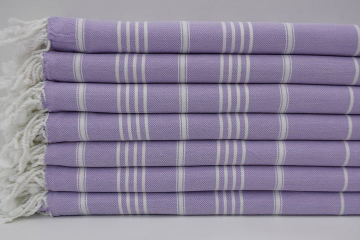 Folded lavender hand towel with white stripe pattern and visible fringed border