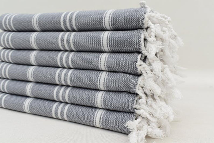 Folded gray hand towel with white bands and fluffy fringed border