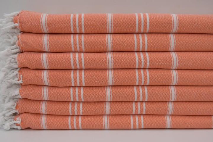 Peach bath hand towel with white stripe pattern and fringed border, neatly folded
