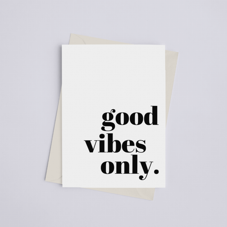 White greeting card with black "good vibes only." text, centered with beige envelope behind