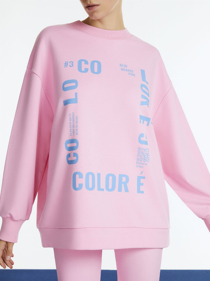 Pink oversized crewneck sweatshirt close-up, multicolor text logo on front