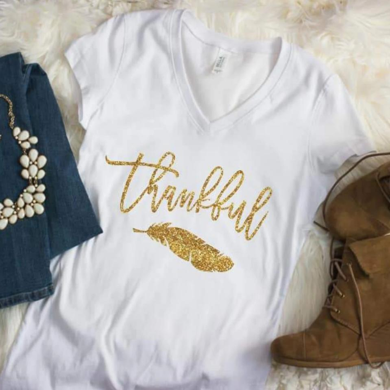 White V-neck T-shirt with gold glitter “Thankful” script and feather graphic