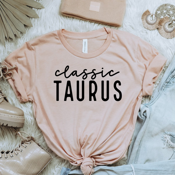 Peach women's crewneck T-shirt with black "Classic TAURUS" zodiac graphic