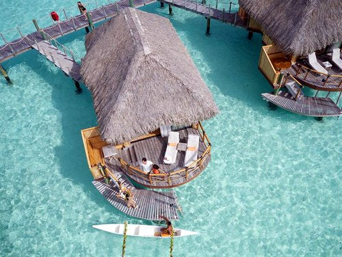 Island Dreams body oil concept: thatched cabana over turquoise resort pool