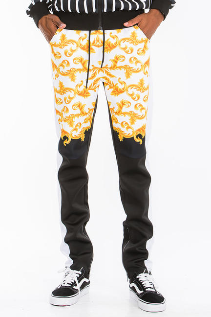 Printed track pants with orange-gold floral scroll pattern and black side panels
