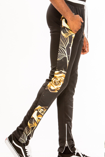 Black printed joggers with gold rose/leaf print, side zipper, ribbed cuffs.