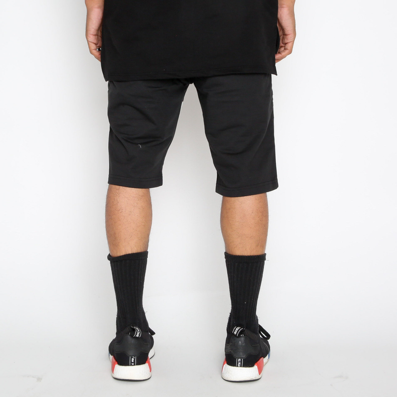 Black moto-style shorts, straight hem, no visible pockets from back; ribbed socks in view