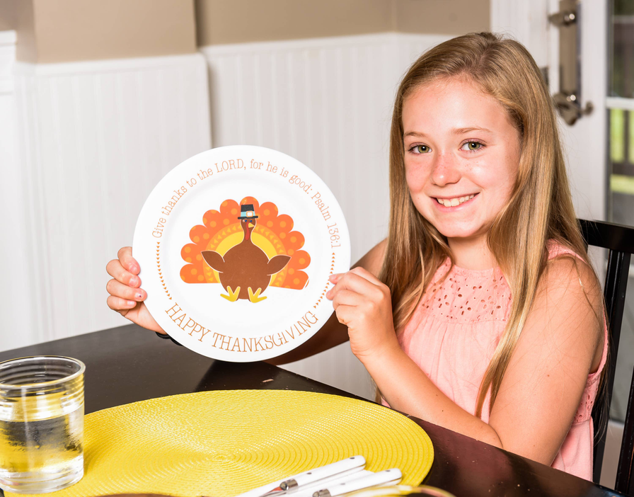 Person holding round Happy Thanksgiving plate with turkey design