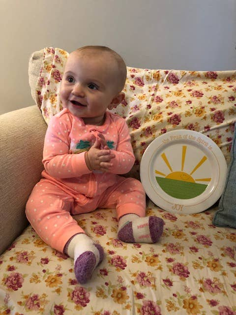 Joy Plate circular plate artwork next to smiling baby on couch