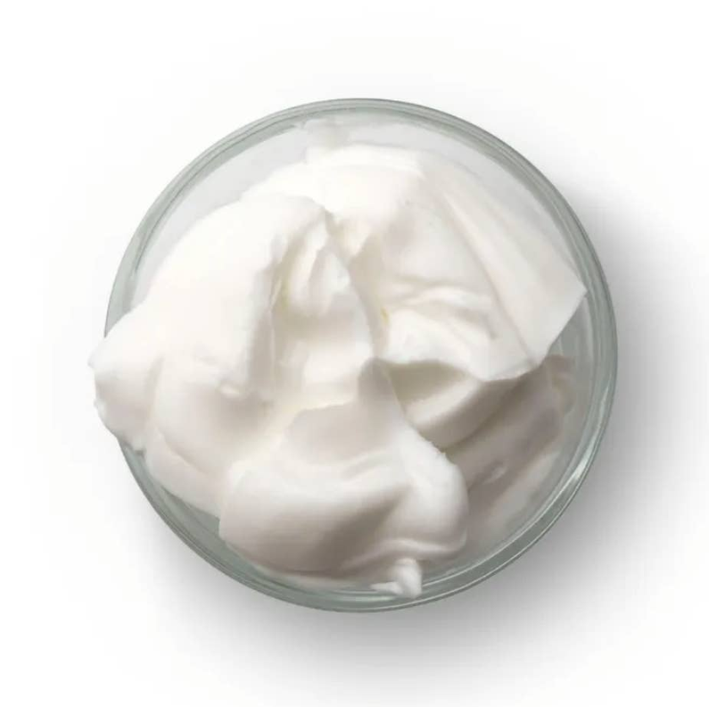 Thick white body cream in a clear glass bowl