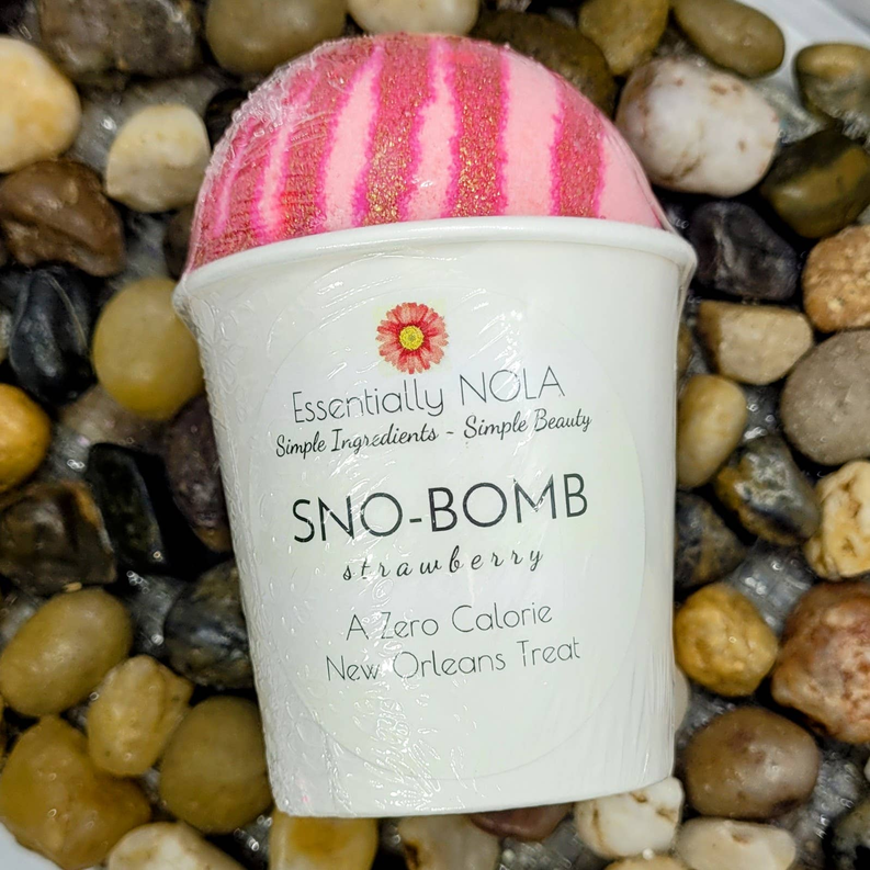 Sno Bomb bath bomb cup with pink striped bath bomb on pebble surface