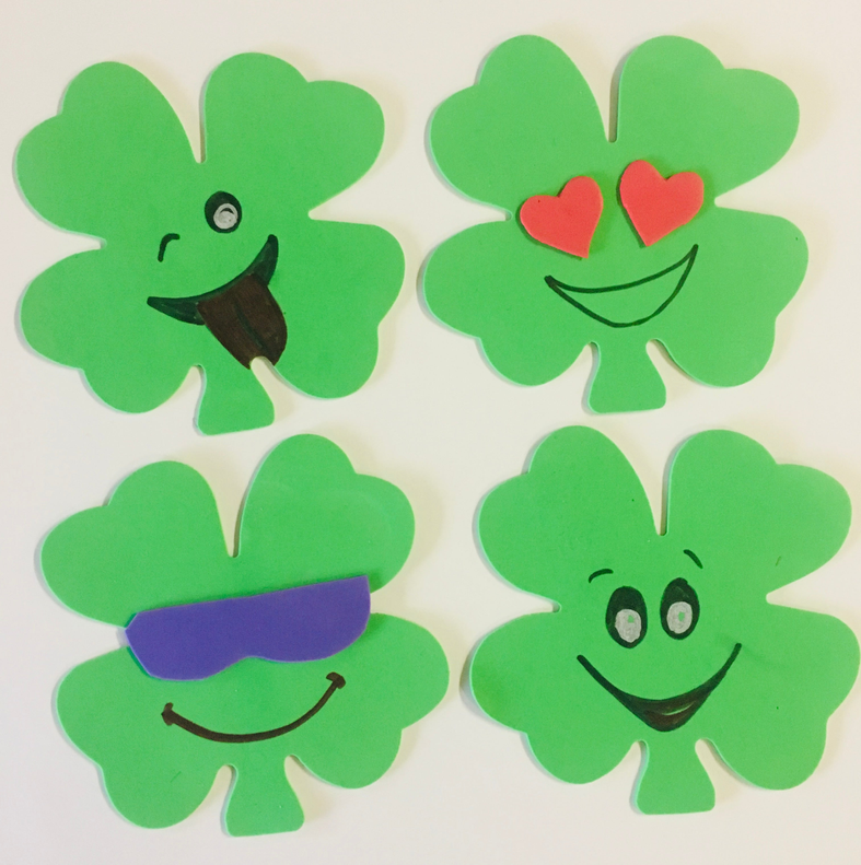 Set of green foam shamrock cut-outs with cartoon faces, hearts, and smiles