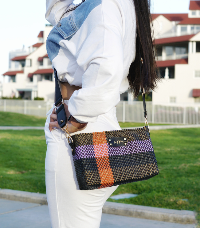 Mini crossbody bag worn crossbody, woven check pattern in orange, purple and black.