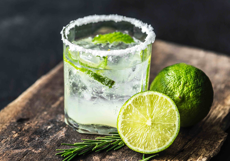 Lime margarita-style drink with salt rim and lime wedges, mixed with cane sugar